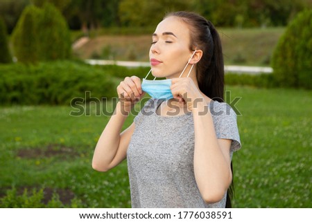Young woman takes off medical mask and breath deeply with closed eyes.