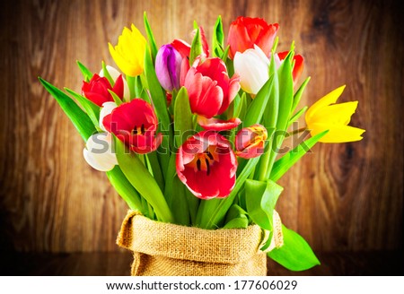 Tulips flowers in the sack on wooden background