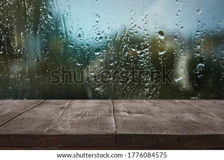 Wooden table near window on rainy day