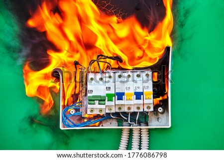 Short circuit and overload in circuit breakers led to electrical fire. Ignition hazard when using faulty wires in a home electric system. Burning switchboard at home. Damaged  wiring is dangerous. Royalty-Free Stock Photo #1776086798