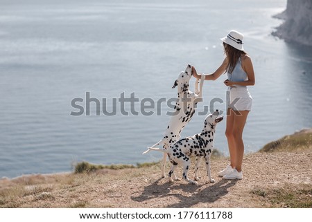 Woman with a dog dalmatian. Girl and her friend dog on the blue sea background