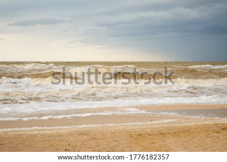 Storm waves roll up on the shore of a sandy beach