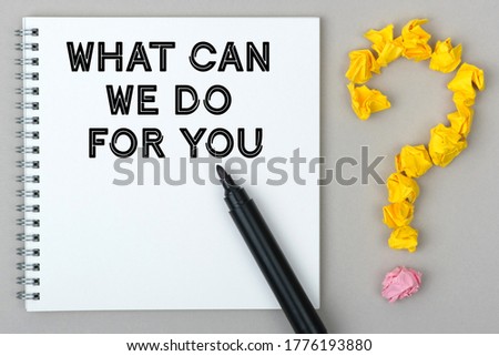 Hand with marker writing: What Can We Do For You. Notepad and question mark.