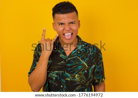 Portrait of a crazy boy showing tongue horns up gesture, expressing excitement of being on concert of band.