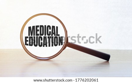 Magnifying glass with text MEDICAL EDUCATION on wooden table.