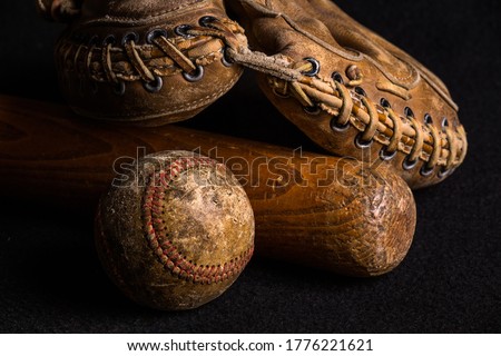 Nostalgic baseball gear from a childhood of many neighborhood games. Baseball, glove and bat all scratched and stained from years of play Royalty-Free Stock Photo #1776221621
