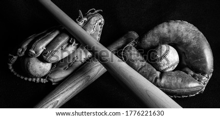 Dark black and white image of old baseball gear that has been well loved. Scratched, scuffed and peeling from years of play. Royalty-Free Stock Photo #1776221630