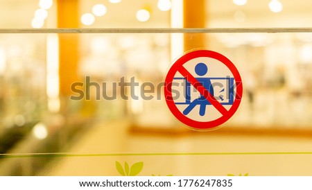 A sign saying 'Do not lean on the glass wall'