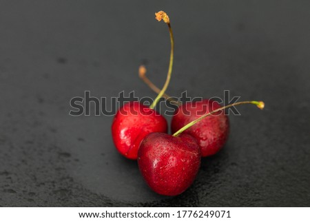Ripe cherry on a black background in the rain. Berry with drops of water. Tasty and healthy food.