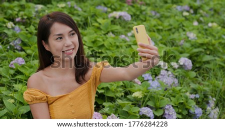 Woman take selfie on cellphone in hydrangea flower field