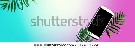 Smartphone with tropical palm leaves - flat lay
