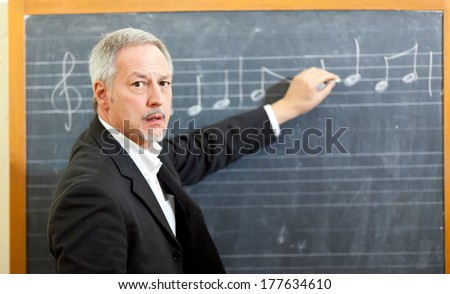 Music teacher writing notes on a blackboard 