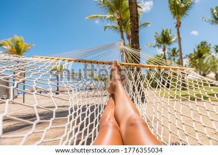 Beach Caribbean travel holiday vacation woman feet selfie lying down relaxing on hammock oustside sunbathing. Girl relaxing taking pov photo of her legs sun tanning in tropical summer destination.