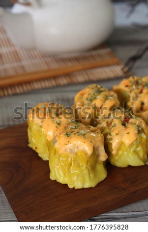 Close up view of Dim Sum Mentai, steamed Chinese dumplings with spicy mayonnaise and seaweed powder for topping, served on wooden tray, selective focus