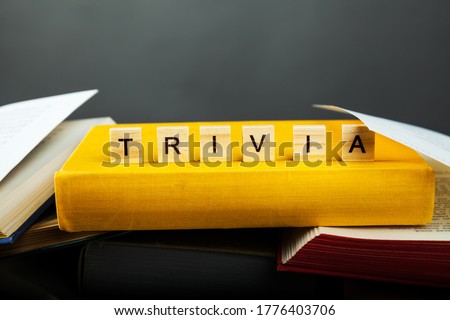 The concept of trivia knowledge. Trivia word from wooden blocks with letters on old and new books are piled up in a careless pile for uselessness, Much knowledge