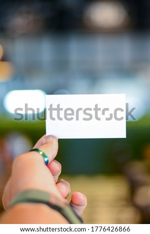 Hand hold blank business card ocver blurred background. Advertisement concept. Business card with copy space. Web design banner.