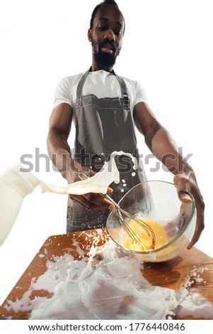 Amazing african-american man preparing unbelievable food with action, details and bright emotions, professional cook isolated on white studio background. Modern kitchen, artwork. Close up, wide angle.