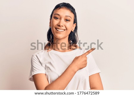 Young woman wearing casual clothes smiling cheerful pointing with hand and finger up to the side 