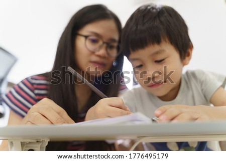Asian boy about 4 years old drawing picture by pencil as home study with his mother