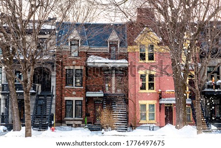 Winter street in Montreal, with traditional style architecture, snow covered balconies and heavy snowfall. Winter or Christmas themed seasonl image.  Royalty-Free Stock Photo #1776497675