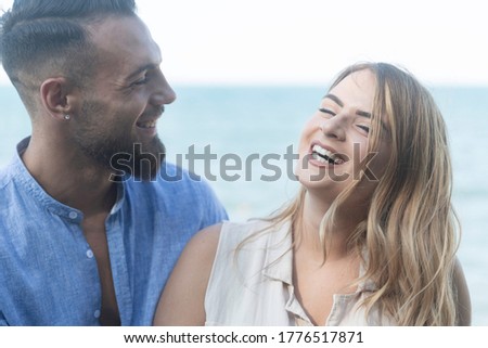 Family picture of a happy couple whit italiana man and Italian woman in a park by the sea he with a beard and she is very cheerful