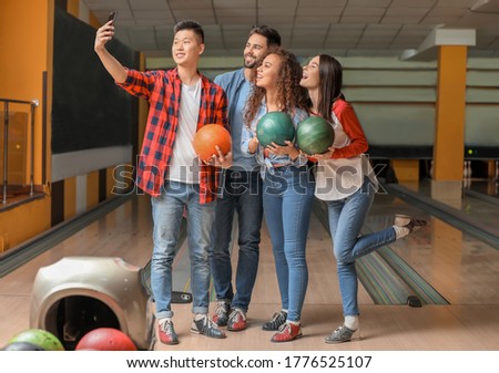 Friends taking selfie while playing bowling in club