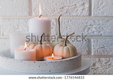 Autumn home decor with white pumpkins and burning candles. Cozy fall composition
