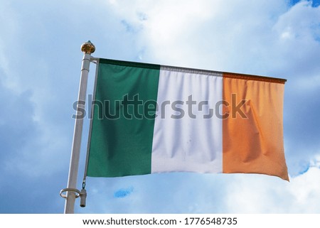 Large flag of IRELAND waving in the wind with a blue sky background