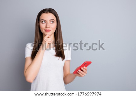 Profile photo of attractive lady hold telephone writing social network post corona virus quarantine theme think what to begin with wear casual white t-shirt isolated grey color background