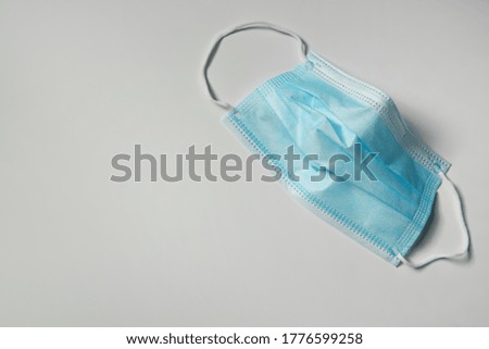Disposable face mask on light background, top view with space for text. Protective measures during coronavirus quarantine