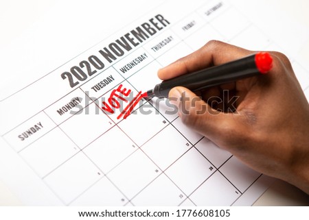African man writing text vote on 2020 November calendar, US elections