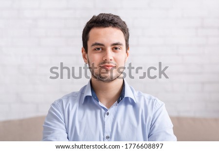 Video meeting and work from home. Portrait of serious man in shirt on white wall background, free space