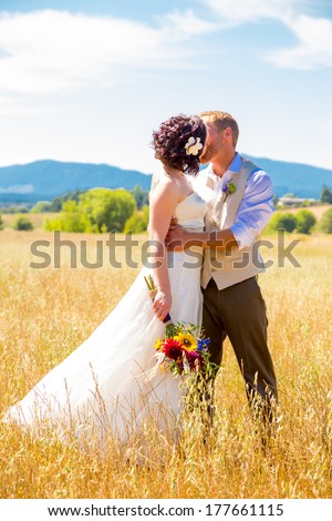 Natural meadow or field plays host for this portrait of the bride and groom on their wedding day after just getting married during their ceremony.