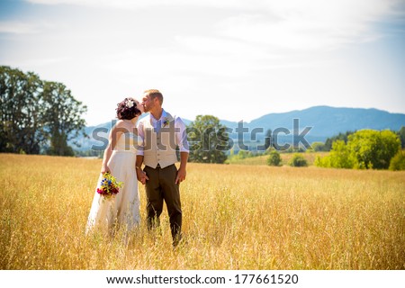 Natural meadow or field plays host for this portrait of the bride and groom on their wedding day after just getting married during their ceremony.
