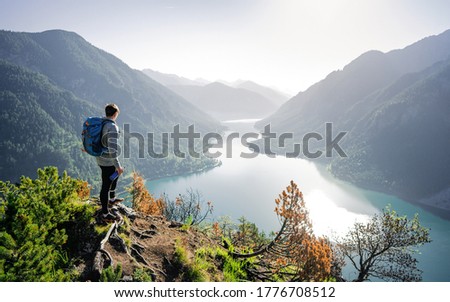 Enjoy the amazing view from top of the world. Hiker take rest for watching the landscape below. Enjoying beautiful view to summer lake with turquoise water 