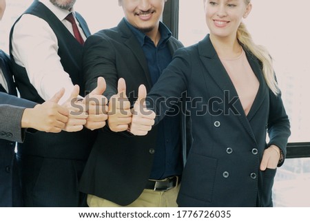 Closeup of professional business people standing and giving thumbs up for positive symbol of successful job and good teamwork in the office. Work encouragement and business growth concept