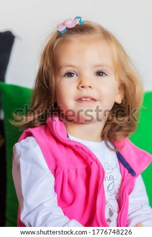 portrait of child with haircut and pink vest, note shallow depth of field
