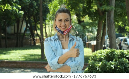 Portrait of female with medical mask with Usa flag. Everything is OK sign.