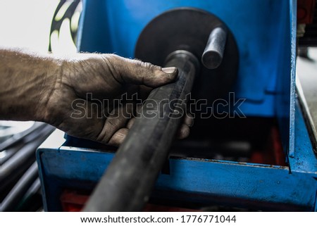 Worker, cutting hydraulic hoses in a metal workshop