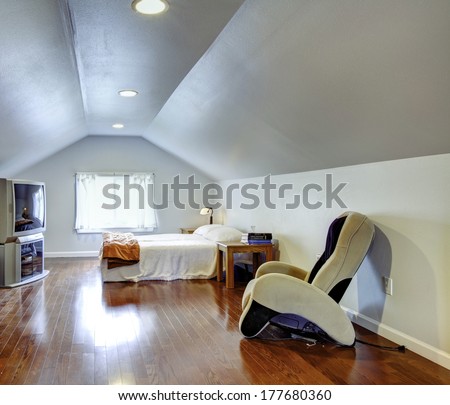 Light blue low and vaulted ceiling bedroom with hardwood floor. Room furnished with bed, tv, nightstand and massage chair