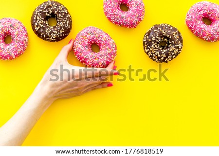 Hand holding glazed donut swith sprinkles, above view