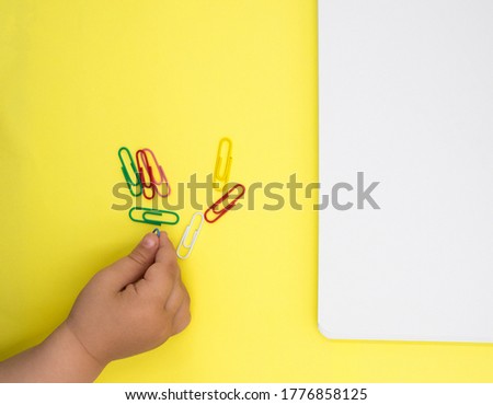 child's hand collecting paper clips. development of fine motor skills of the hands. Technique Montessori.
Children's hand on a table with colored paper.  Royalty-Free Stock Photo #1776858125