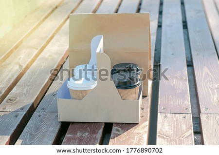 Cardboard cup of coffee and package with food on wooden background, take away concept