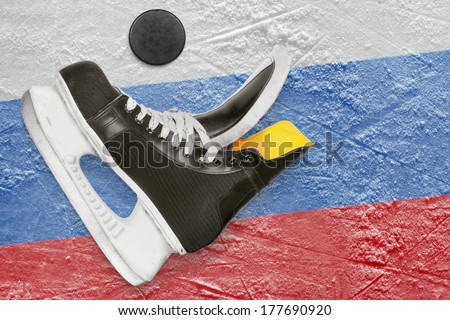 Puck, skates and the image of the Russian flag on the ice