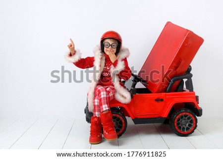 A cute boy dressed as Santa makes a gesture of attention. White background.