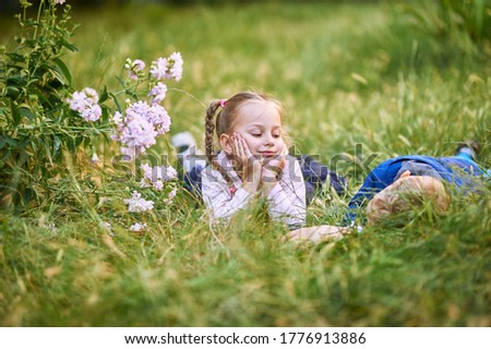 little girl sitting on the grass with a boy. Girl laughs while boy up his legs. High quality photo