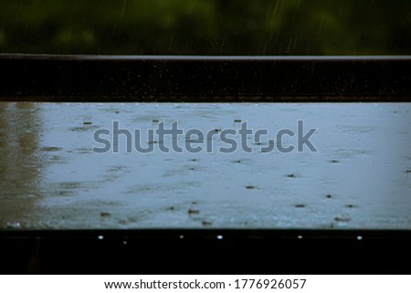  rain drops falling into a water puddle with water splashing