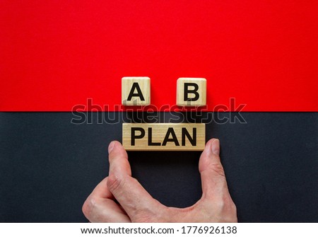 Businessman holds a block with word 'plan'. Wooden cubes with letters A and B. Beautiful red and black background. Copy space. Concept of choice.