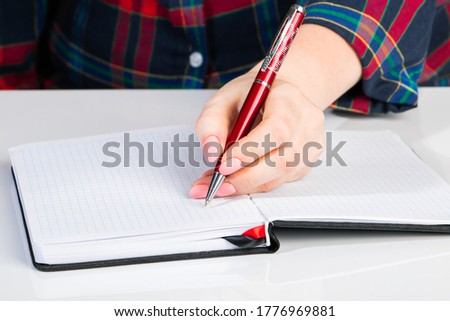Left-handers Day. Business woman writes a note in a notebook. Girl holds a pen in her left hand close-up.