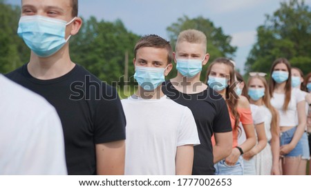 Pandemic concept. A group of students stand in a row in masks.